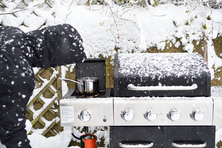 Close up of a man cooking on the barbecue during a snow stormの写真素材