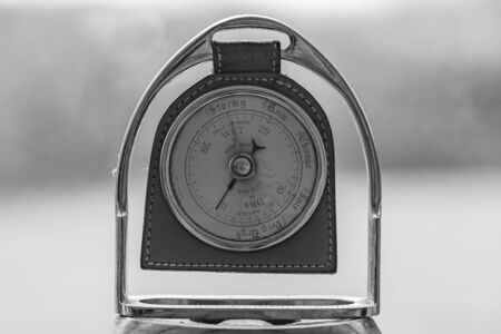 Close up of an old antique barometer made out of an old horses stirrup  indicating high pressure and fine weather.の写真素材