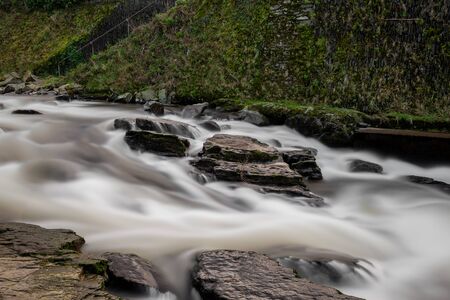 Long exposure of the East Lyn river flowing over rocks in Lymnouth in Devonの写真素材