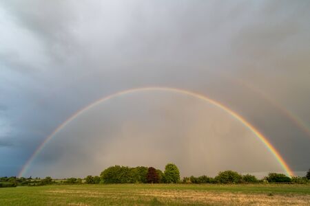 Landscape photo of a rainbow in a field