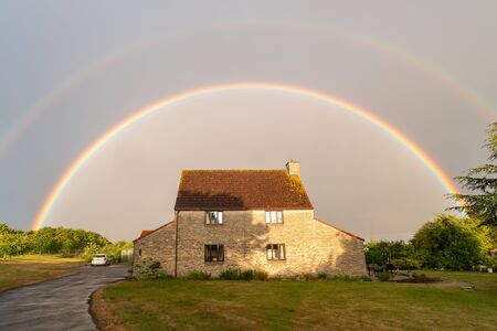 View of a full rainbow over the top of a houseの写真素材