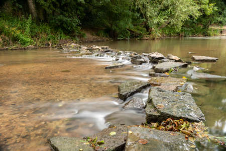 Long exposure of the River Brue flowing through the weir at West Lydford in Somersetの写真素材