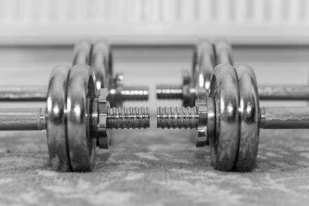 Black and white photo of dumbbells on the floor at homeの写真素材