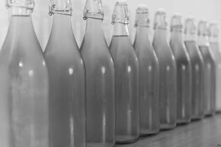 Black and white photo of a row of flip top bottles of home made cider covered in condensationの写真素材