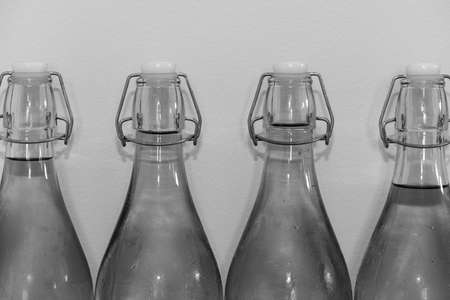 Black and white photo of a row of flip top bottles of home made cider covered in condensationの写真素材