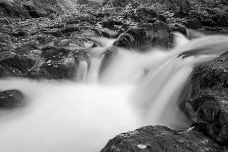 Long exposure of a waterfall on the East Lyn river flowing through the woods at Watersmeet in Exmoor...