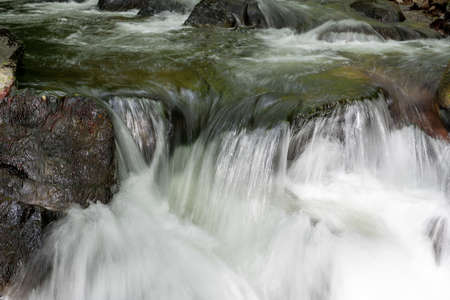 Long exposure of a waterfall on the East Lyn river flowing through the woods at Watersmeet in Exmoor...