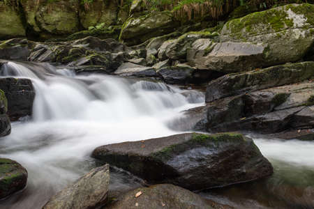 Long exposure of a waterfall on the East Lyn river flowing through the woods at Watersmeet in Exmoor National Parkの写真素材