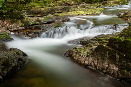 Long exposure of a waterfall on the East Lyn river flowing through the woods at Watersmeet in Exmoor...