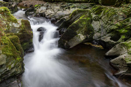 Long exposure of a waterfall on the East Lyn river flowing through the woods at Watersmeet in Exmoor National Parkの写真素材
