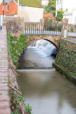 Long exposure of a watefall flowing under a bridge on the River Lim walkway at Lyme Regis in Dorset.の写真素材