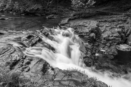Long exposure of a waterfall on the East Lyn river flowing through the woods at Watersmeet in Exmoor...