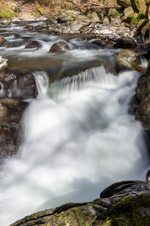 Long exposure of a waterfall on the East Lyn river flowing through the woods at Watersmeet in Exmoor National Parkの写真素材