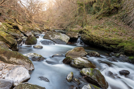 Long exposure of a waterfall on the East Lyn river flowing through the woods at Watersmeet in Exmoor National Parkの写真素材