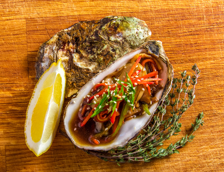 Salad in oyster served with greens and lemon on a wooden backgroundの写真素材