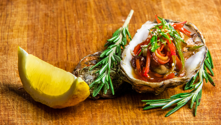 Salad in oyster served with greens and lemon on a wooden backgroundの写真素材