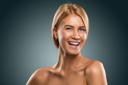 Portrait beautiful blond woman with blue eyes smiling in azure background.の写真素材