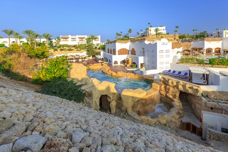 Panorama of white city at a tropical luxury resort hotel set in neat manicured lawns with ornamental shrubs, palm trees, swimming pools, Egyptの写真素材