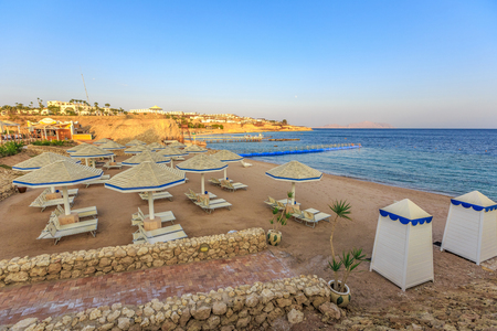 Beach with deck chairs and parasol at the luxury hotel during sunsetの写真素材