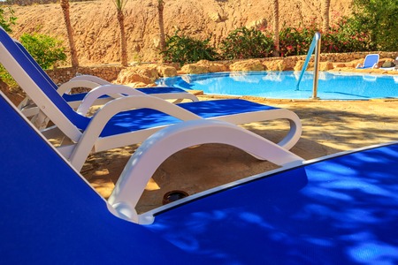 Closeup several of sun loungers by a beautiful swimming pool. Exotic vacation by the hotel pool in bright sunshine, Egypt.の写真素材