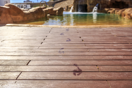 Closeup footprints on the wooden floor behind it swimming pool with artificial waterfall  on a beautiful resort in Egyptの写真素材