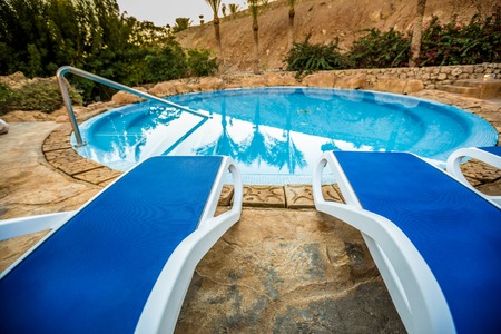 Sunloungers and beautiful swimming pool with reflected of palm trees in a blue water, Egypt.の写真素材