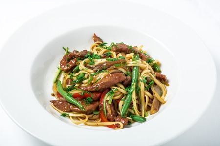 Thai noodles with ostrich meat, green beans and mushrooms in white plate. Thai dish with a...