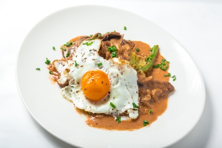 Veal with parsnip puree, asparagus and miso mushroom sauce served with a fried egg in white plate. Close-up top viewの写真素材