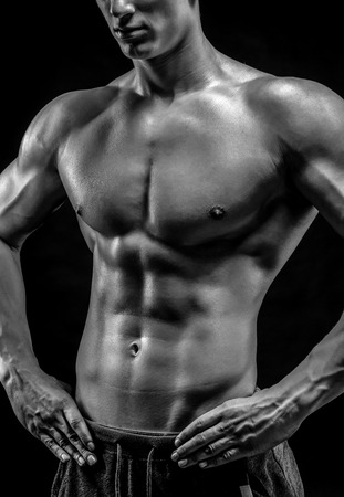 Close-up of a power fitness man. Strong man with muscles and biceps on black background. Black and whiteの写真素材