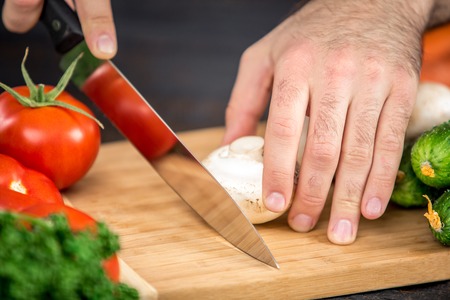Close up on male hands cutting tomato, making salad. Chief cutting vegetables. Healthy lifestyle, diet foodの写真素材