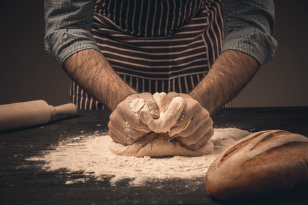 Male hands knead the dough. Chef cooking bread and bunの写真素材