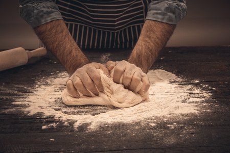 Male hands knead the dough. Chef cooking bread and bunの写真素材