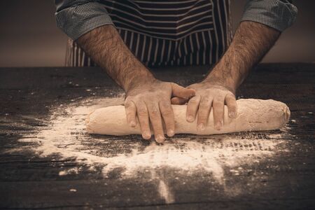 Male hands knead the dough. Chef cooking bread and bunの写真素材