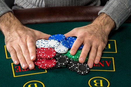 Poker play. Chips on the green table. chips in male handsの写真素材