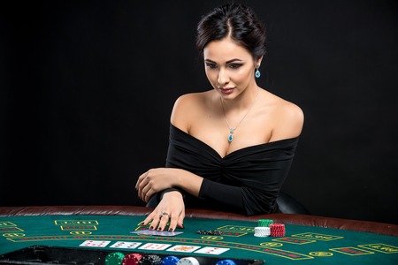 sexy woman with poker cards and chips. Female player in a beautiful black dressの写真素材