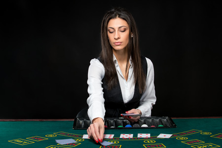 The beautiful girl, dealer, behind a table for game in poker. the dealer deals the cards.の写真素材