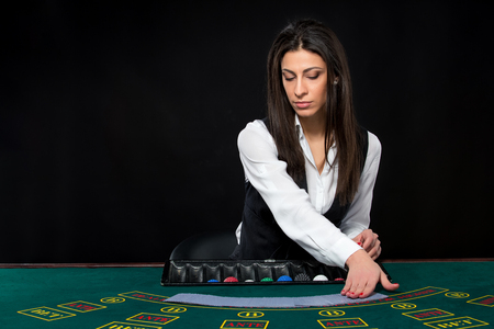 The beautiful girl, dealer, behind a table for game in poker. the dealer deals the cards.の写真素材