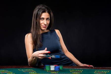 sexy woman with poker cards and chips. Female player in a beautiful black dress. throws a card.の写真素材