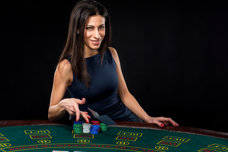 sexy woman with poker cards and chips. Female player in a beautiful black dress. throws a card.の写真素材