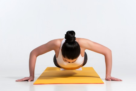 A young sportswoman performing a plank exercise on an yellow mat. look at the cameraの写真素材