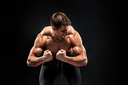 Fitness man model torso posing and showing perfect body, shoulders, biceps, triceps and chest on black background.の写真素材
