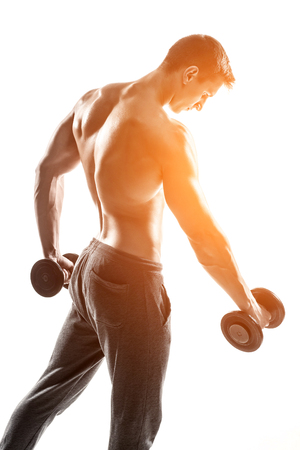 Handsome muscular man doing exercises with dumbbells isolated on white background Whith solar flareの写真素材