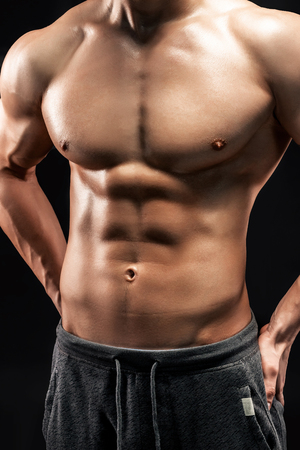 Close-up of a power fitness man. Strong man with muscles and biceps on black background.の写真素材