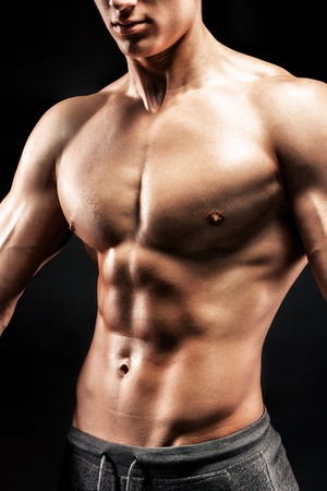 Close-up of a power fitness man. Strong man with muscles and biceps on black background.の写真素材