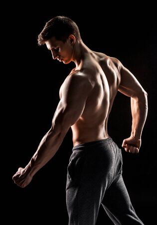 Strong bodybuilder man posing with perfect abs, houlders,biceps, triceps and chest on black background.の写真素材