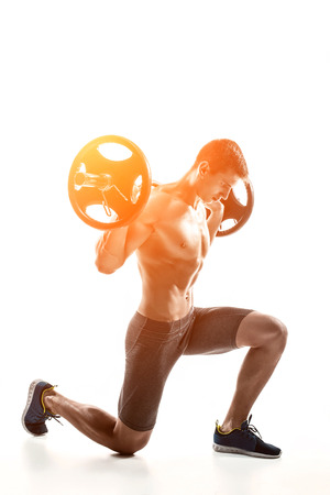Muscular mighty man standing on knee and holding barbell over his head. Isolated on white background. Whith solar flareの写真素材