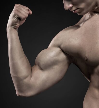 Image of very muscular man posing with naked torso in studio and looking behind on black background. Close upの写真素材