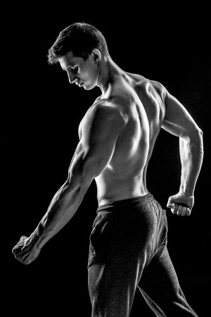 Strong bodybuilder man posing with perfect abs, houlders,biceps, triceps and chest on black background. Black and whiteの写真素材
