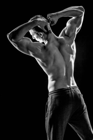 Strong bodybuilder man posing with perfect abs, houlders,biceps, triceps and chest on black background. Black and whiteの写真素材
