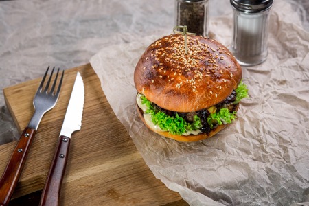 Burger on the wooden table with with knife and fork. burger with lambの写真素材